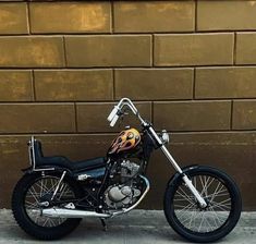 a motorcycle parked in front of a brick wall with flames painted on the back tire