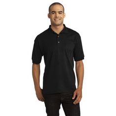 a man standing in front of a white background wearing a black polo shirt and jeans