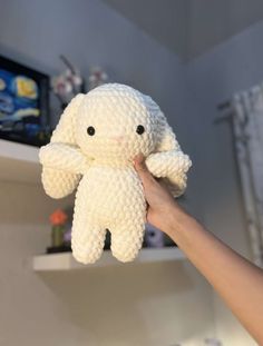 a person holding a white stuffed animal in their hand