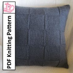 a gray knitted pillow sitting on top of a white couch