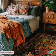 a bed sitting next to a window covered in lots of pillows on top of a rug