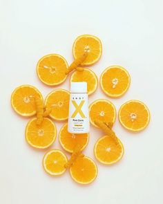 oranges arranged in the shape of a x on a white background with a bottle