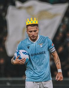 a man with a crown on his head holding a soccer ball