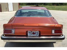 an orange car parked in a driveway with the license plate on it's front