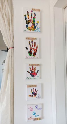 three handprints are hung on the wall in front of a white drapes