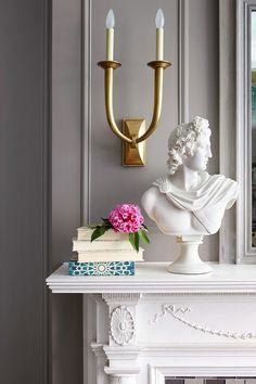 a white busturine on a mantle next to a candle holder and bookend