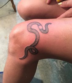 a woman's leg with a tattoo on it that is shaped like a snake