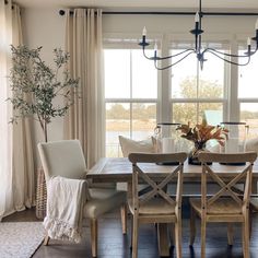 a dining room table with chairs and a vase filled with flowers on top of it