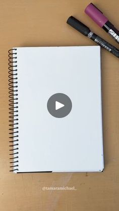 an open notebook with markers and pens on it