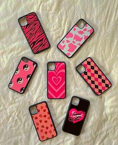 six cell phone cases are arranged in a circle on a white sheet with pink and black designs