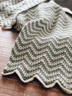 two crocheted blankets sitting on top of a wooden table