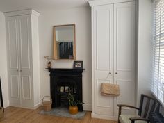 a living room with white walls and wood flooring is pictured in this image, the fireplace has a mirror on it