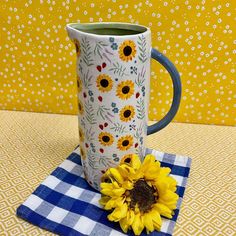 a sunflower sitting on top of a blue and white checkered napkin next to a coffee mug