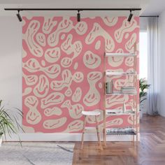 a pink and white abstract wall mural in an empty room with wooden flooring, bookshelf and plant