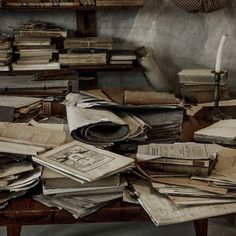 many old books are piled on top of each other in a room full of shelves