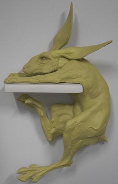 a clay sculpture of a leaping rabbit on a shelf