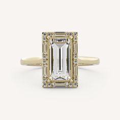 an emerald cut diamond ring with diamonds around the band and side stones in yellow gold