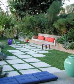 a garden with grass, plants and benches in the middle of it is surrounded by greenery