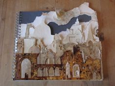 an altered photo of a castle on top of a wooden table with torn up paper