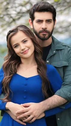 a man and woman standing next to each other in front of a tree with flowers