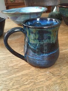 three blue and green cups sitting on top of a wooden table next to each other