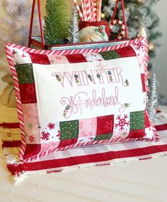 a red and white pillow sitting on top of a table next to a christmas tree