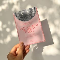 a person holding up a pink birthday card with disco ball on the front and back