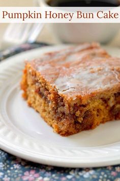 a piece of cake on a white plate with a cup of coffee in the background