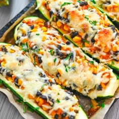 zucchini stuffed with black beans, corn and cheese in a baking pan on a wooden table