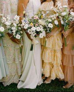 a group of women standing next to each other in dresses and holding bouquets with flowers