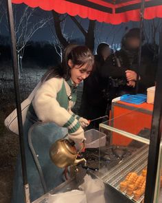 a woman is making donuts at an outdoor stand