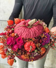 a person holding a red pumpkin decorated with flowers