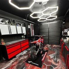 a motorcycle is parked in a garage with red and black paint on the floor,