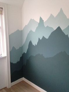 a room with a mountain mural painted on the wall and wood flooring in front of it