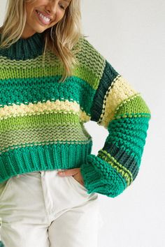 a woman is wearing a green and yellow striped sweater with white pants on the side