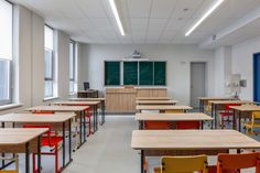 an empty classroom with many desks and chairs in front of a chalkboard on the wall