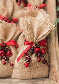 burlap bags filled with red berries and pine cones on top of a wooden bench