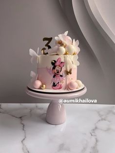 a minnie mouse birthday cake on a white pedestal with marble counter top and grey background