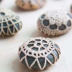 some rocks are sitting on a table with crocheted designs and beads around them