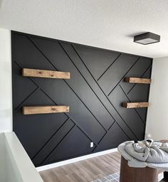 an empty room with black walls and wooden shelves on the wall, in front of a white