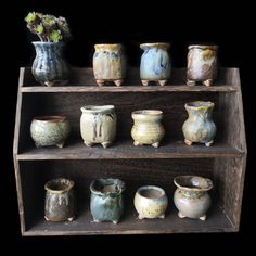 an assortment of vases are displayed on wooden shelves