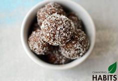 a bowl filled with chocolate covered donuts on top of a white tablecloth next to a blue wall