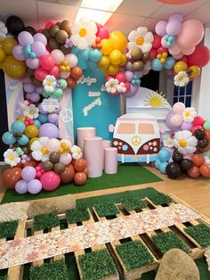 a party with balloons and decorations on the floor, including fake grass in front of a vw camper van