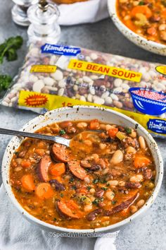 two bowls of beans, carrots and sausage soup on top of a gray table