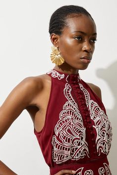 a woman in a red dress with gold earrings on her head and hands on her hips