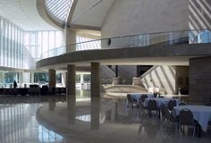 the inside of a large building with tables and chairs in front of windows on both sides