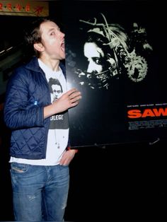 a man standing in front of a movie poster with his mouth open and tongue out