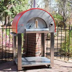 an outdoor brick pizza oven sitting next to a fence