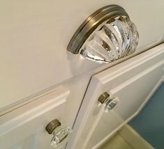 a close up of a door handle on a white cabinet with clear glass knobs