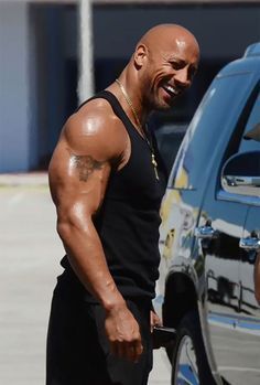 a man in black shirt and shorts standing next to a car